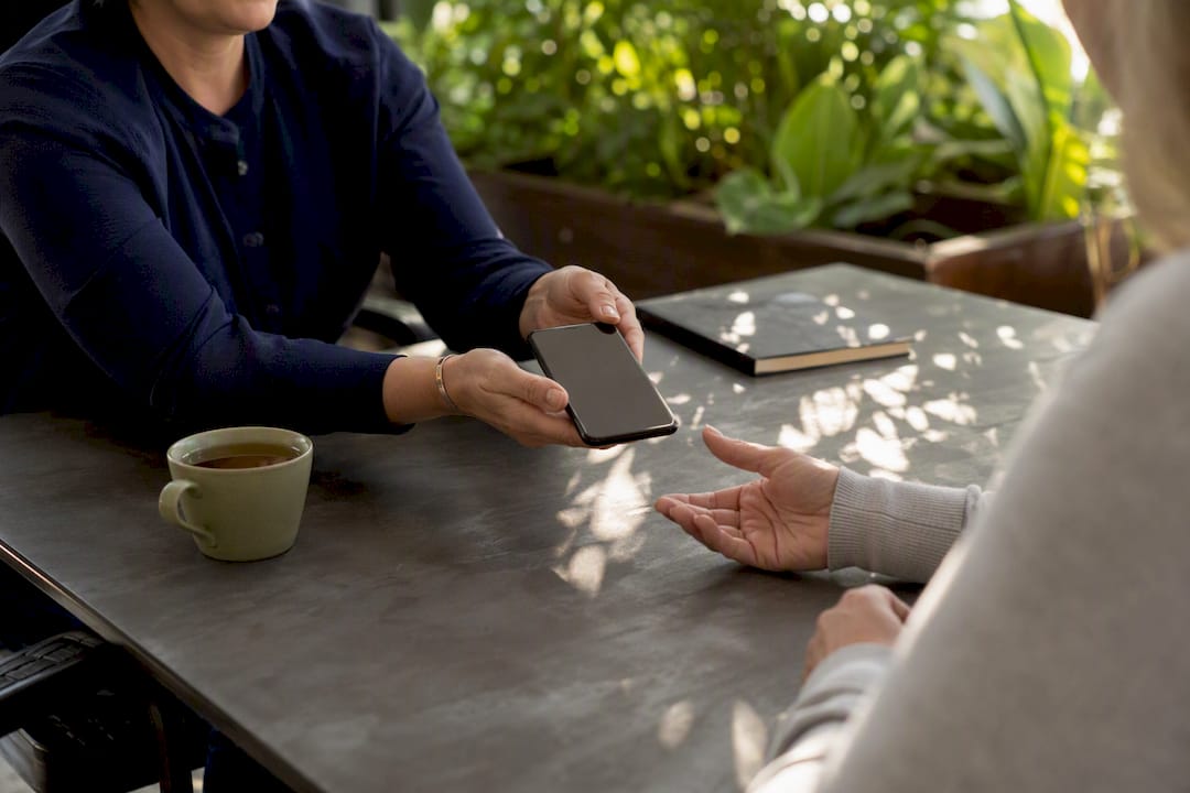 Hands passing phone for warm handoff