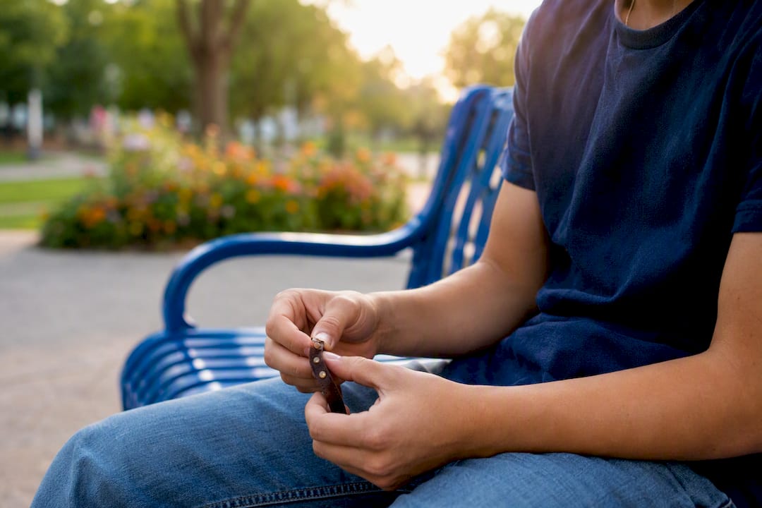 Teen hands twisting bracelet nervously on park bench