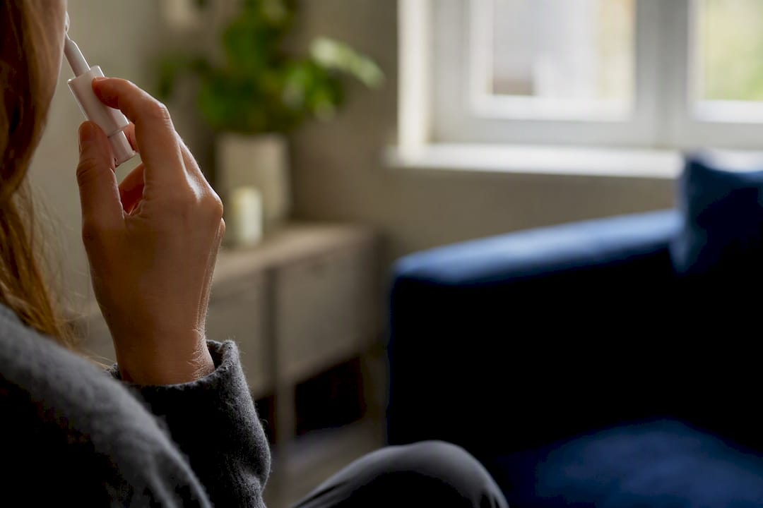Hand holding nasal spray device before use